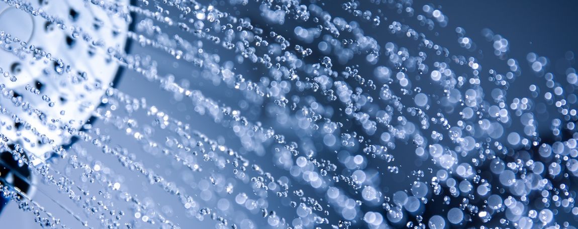 Watts Industries Shower head sprinkling water in front of blue background