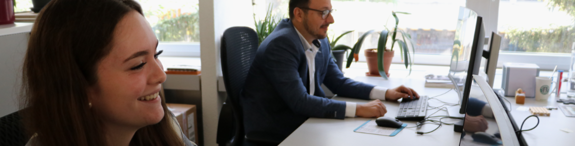 Apprentice and trainee working side by side on a computer