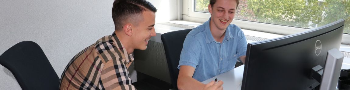 Apprentice and trainer working together in front of a computer