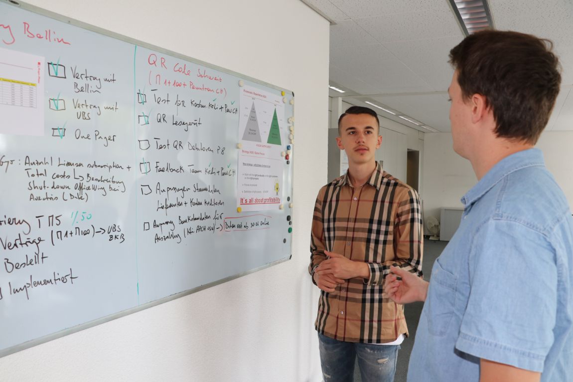 Apprentice solving a task on whiteboard with advice from trainer