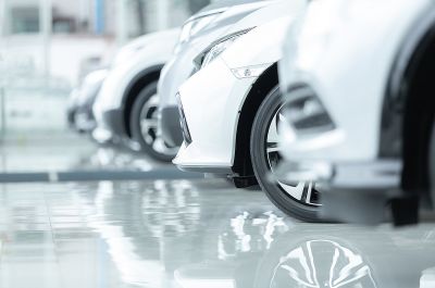 Automotive industry: white cars lined behind each other with their shadows reflecting on the floor