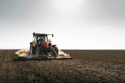 Agriculture and construction machinery industry: tractor pelleting or harvesting a brown field